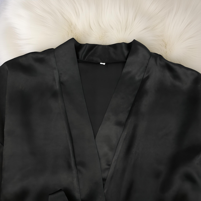 Black satin robe on a white fur surface